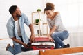 African-american couple trying to close suitcase on bed