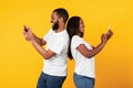 African american couple using smartphones, yellow studio wall Royalty Free Stock Photo