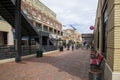 An African American couple walking along a red brick footpath with red benches and red brick buildings and a black metal staircase