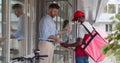 African-American courier in safety mask handing fresh food to young businessman customer Royalty Free Stock Photo