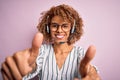 African american curly call center agent woman working using headset over pink background approving doing positive gesture with Royalty Free Stock Photo