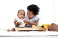 African American curly hair girl trying to feed her little sister with spoon of food, infant eating healthy homemade baby food, Royalty Free Stock Photo