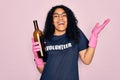 African american curly woman wearing volunteer t-shirt doing volunteering recycling glass bottle very happy and excited, winner