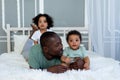 African-American dad plays with kids babies at home on the bed in the bedroom and cuddle, father`s love