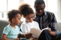 African American dad reading book to small kids