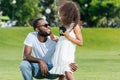 african american daughter standing with police badge and touching father beard