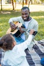 african american daughter touching guitar while her father playing