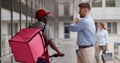 African-American delivery man asking caucasian businessman for direction outside business center