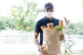 African American delivery man with medical mask holding fresh grocery in paper bag of food to customer home.Delivery service under