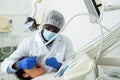 African american dentist is treating female patient which is sitting in chair Royalty Free Stock Photo