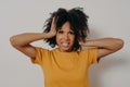 African American distressed woman losing control over emotions, closing her ears with hands tightly