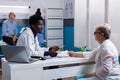 African american doctor consulting old woman at desk Royalty Free Stock Photo