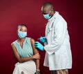 African american doctor giving covid vaccine to black woman wearing surgical face mask. Healthy patient getting corona