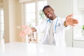 African american doctor man at the clinic looking at the camera smiling with open arms for hug Royalty Free Stock Photo