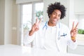 African American doctor man at the clinic smiling looking to the camera showing fingers doing victory sign Royalty Free Stock Photo