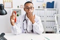 African american doctor man holding ear otoscope at the clinic covering mouth with hand, shocked and afraid for mistake Royalty Free Stock Photo