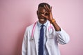 African american doctor man wearing stethoscope standing over isolated pink background doing ok gesture with hand smiling, eye Royalty Free Stock Photo