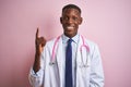 African american doctor man wearing stethoscope standing over isolated pink background pointing finger up with successful idea Royalty Free Stock Photo