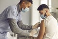 African-American doctor in medical face mask giving antiviral vaccine to young patient Royalty Free Stock Photo