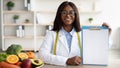 African american doctor nutritionist holding blank clipboard, showing mockup for right nutrition menu, copy space Royalty Free Stock Photo