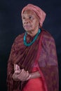 African american elderly lady dressed in shades of red and turban in dignified attitude