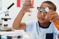 African american elementary boy looking at orange chemical in test tube during chemistry practical Royalty Free Stock Photo