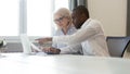 African american employee pointing at laptop discussing paperwork with colleague Royalty Free Stock Photo