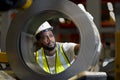 African American engineer worker is examining the stainless galvanized metal sheet roll inside the warehouse factory for roofing Royalty Free Stock Photo