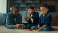 African American ethnic man father with two little preschool sons boys children play game lying on floor at home dad Royalty Free Stock Photo