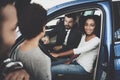 African american family at car dealership. Salesman is showing new car. Royalty Free Stock Photo