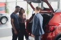 African american family at car dealership. Salesman is showing trunk of new red car Royalty Free Stock Photo