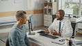 African American Family Doctor is Talking with Young Male Patient During Consultation in a Health Royalty Free Stock Photo