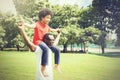 African American family doing piggyback and having fun in the outdoor park during summer.