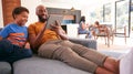 African American Family At Home With Father And Son Sitting On Sofa At Home Using Digital Tablet Royalty Free Stock Photo