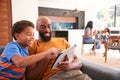 African American Family At Home With Father And Son Sitting On Sofa At Home Using Digital Tablet Royalty Free Stock Photo