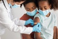African american family making vaccination at clinic, wearing face masks