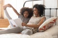 African mom and little kid daughter read book in bed