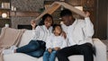 African american family parents with daughter little girl adopted child sit on sofa under cardboard roof dreaming about Royalty Free Stock Photo