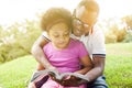 African American family reading a book together in the outdoor park. Royalty Free Stock Photo