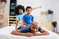 African American family of three, kids sitting on father`s back at home Royalty Free Stock Photo