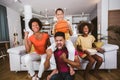 African American family of three watching tv and cheering basketball games on sofa at home