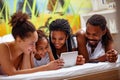 African American Family using tablet while lying together on bed Royalty Free Stock Photo