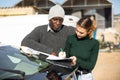African american farmer and female worker signing work contract near car