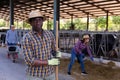 African american farmer holding agricultural tool and standing in cowshed