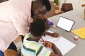 African American father assists a young son with homework at a table with copy space