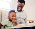 African american father bonding with his at home. Black male helping his son read a book and practice learning while