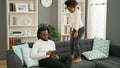 African american father and daughter sitting on sofa working while child disturb at home