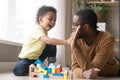 African American father with toddler son playing with wooden constructor