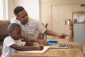 African American father helping his son with homework on laptop at table Royalty Free Stock Photo