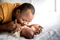 African American father kissing hand, his 12-day-old baby newborn son lying in bed Royalty Free Stock Photo